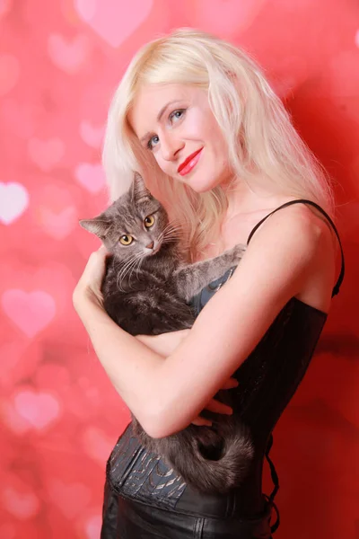Молодая привлекательная девушка с симпатичной взрослой кошкой на студийном фоне — стоковое фото
