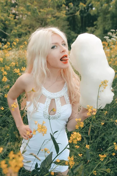 Charmant volwassen blond meisje eten van katoen snoep op de natuur in het park alleen — Stockfoto