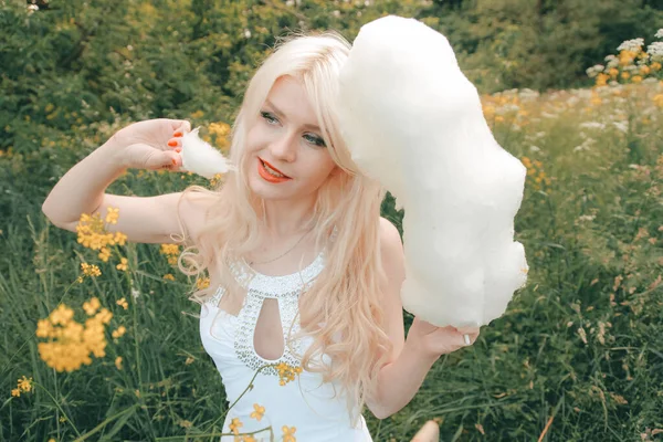 Чарівна доросла блондинка їсть бавовняні цукерки на природі в одному парку — стокове фото