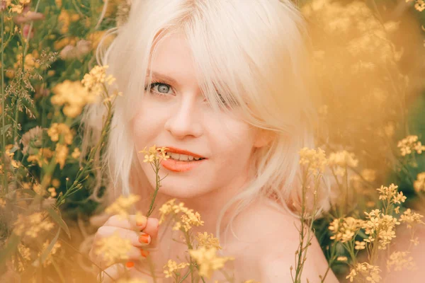 Bela jovem loira no prado com flores amarelas em um dia quente de verão — Fotografia de Stock