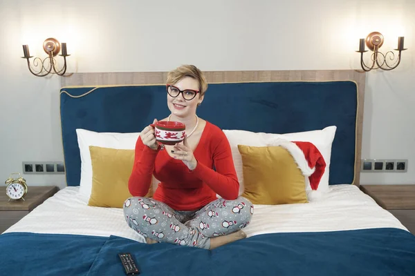 Hermosa mujer con taza de café sentada en la cama en su dormitorio — Foto de Stock