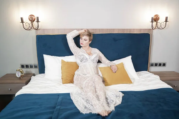 Сексуальна блондинка плюс розмір коротке волосся жінка в прозорій сукні в нижній білизні на фоні спальні — стокове фото