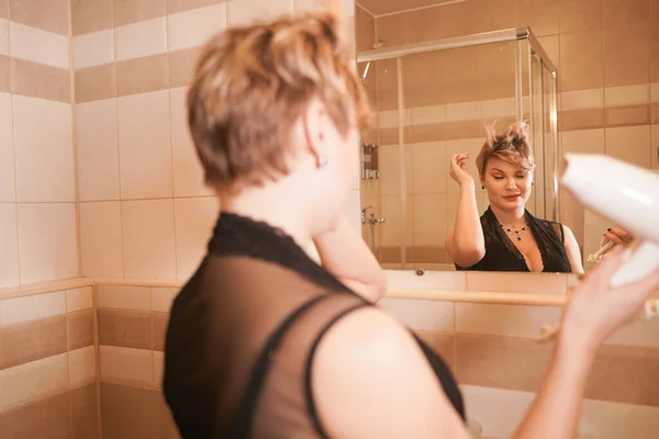 Фото радостной женщины, высушивающей волосы после мытья в ванной возле зеркала . — стоковое фото