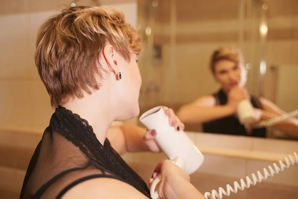 Foto van vrolijke vrouw drogen haar haar na het wassen in de badkamer in de buurt van de spiegel. — Stockfoto