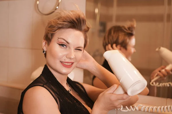 Фото радостной женщины, высушивающей волосы после мытья в ванной возле зеркала . — стоковое фото