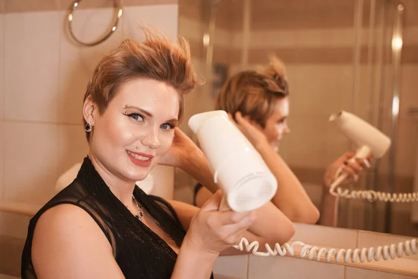 Foto van vrolijke vrouw drogen haar haar na het wassen in de badkamer in de buurt van de spiegel. — Stockfoto