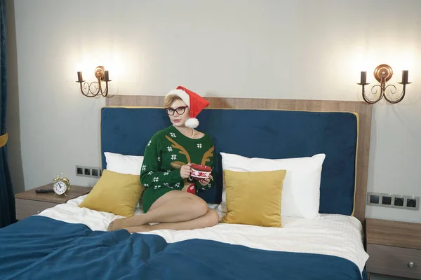 Sevimli, iri yarı, gözlüklü, yeşil Noel kazaklı, ren geyiği ve kırmızı Noel Baba şapkalı bir kız. — Stok fotoğraf