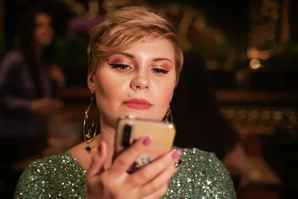 Mujer bonita con teléfono inteligente en la cafetería de la noche — Foto de Stock