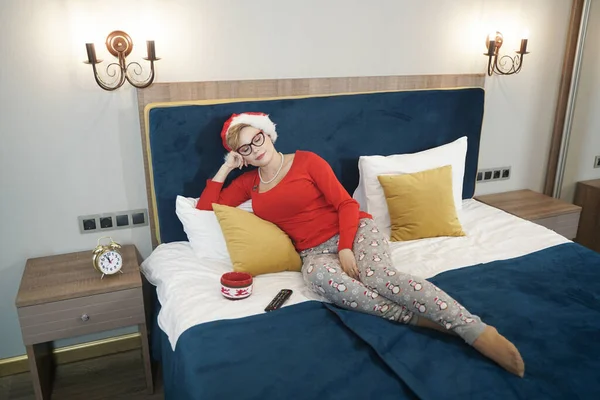 Jovem mulher em camisola de Natal vermelho assistindo TV na cama — Fotografia de Stock