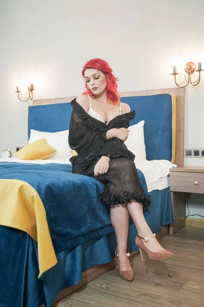 Mujer joven cabeza roja en lencería beige y negro posando en la cama azul en su dormitorio —  Fotos de Stock