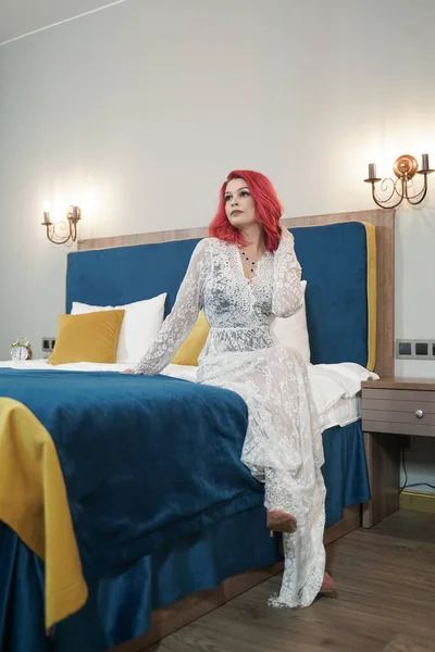Hermosa novia chica con rojo bob corte de pelo en encaje vestido largo posando en su dormitorio solo —  Fotos de Stock