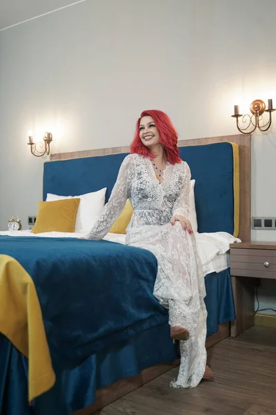 Hermosa novia chica con rojo bob corte de pelo en encaje vestido largo posando en su dormitorio solo —  Fotos de Stock