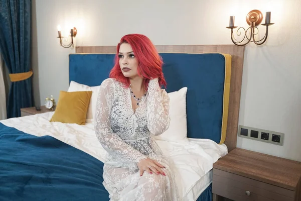 Vacker brud flicka med röd bob frisyr i spets lång klänning poserar i hennes sovrum ensam — Stockfoto