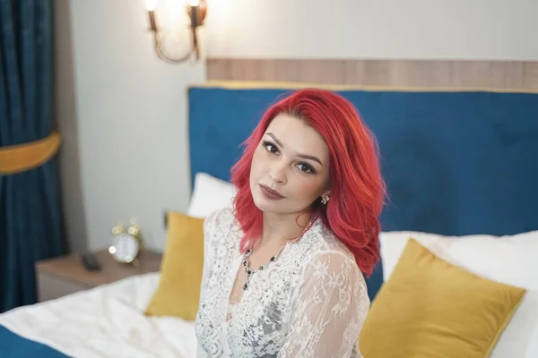 빨간 보브 헤어에 레이스긴 드레스를 입고 홀로 침실에 누워 있는 아름다운 신부 아가씨 — 스톡 사진