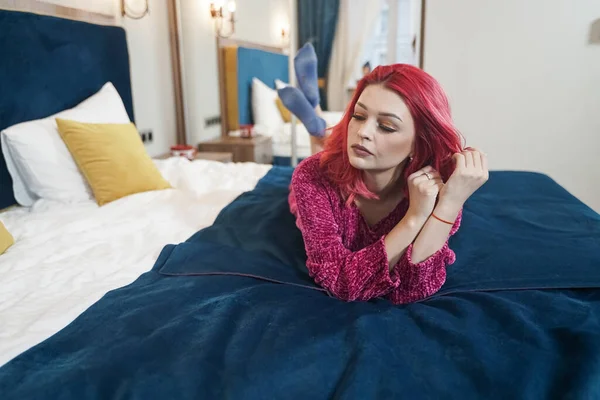 Όμορφη νεαρή κοκκινομάλλα γυναίκα σε ζεστό oversize πουλόβερ στο κρεβάτι — Φωτογραφία Αρχείου
