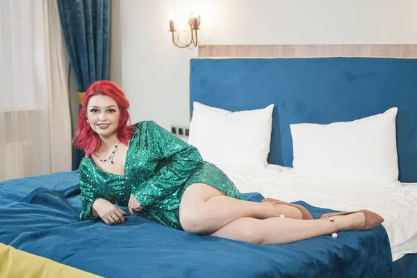 Sexy mujer en verde elegante vestido brillante brillante listo para la fiesta de Navidad y relaz esperando en su cama solo — Foto de Stock