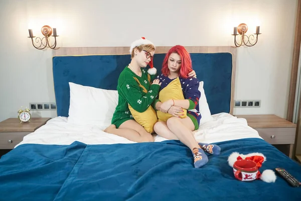 Dwie smutne nieszczęśliwe dziewczyny siedzące na łóżku i przytulające się w święta Bożego Narodzenia — Zdjęcie stockowe