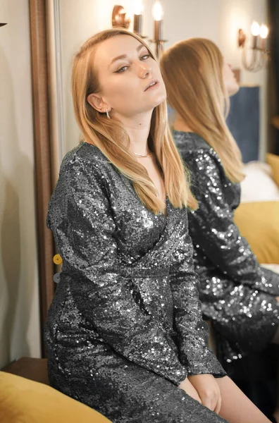 Girl trying dress in looking in mirror cheerful and happy. Cute beautiful Caucasian young woman in black glitter evening dress. — Stock Photo, Image