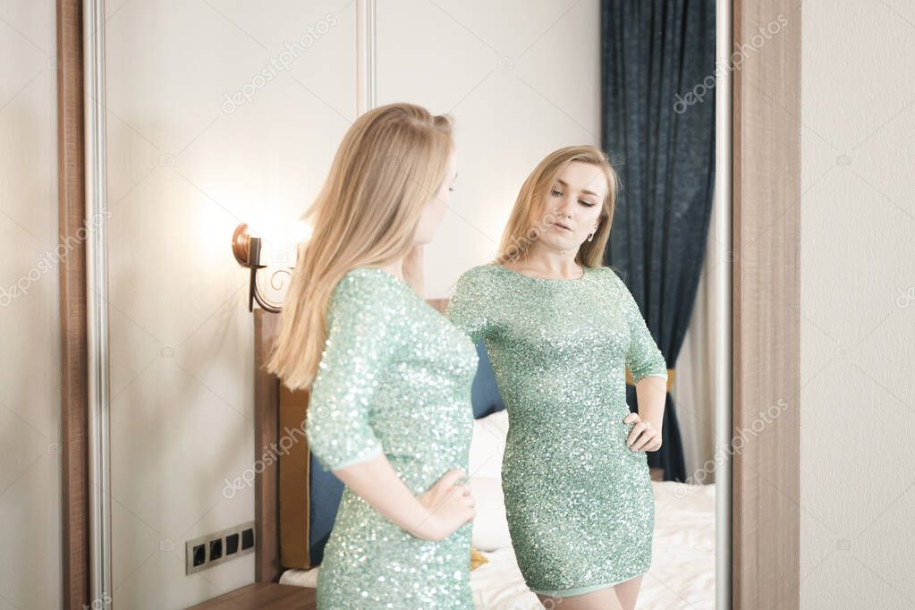 pretty young woman in tight short glitter evening dress ready for party and looking at the mirror on yourself