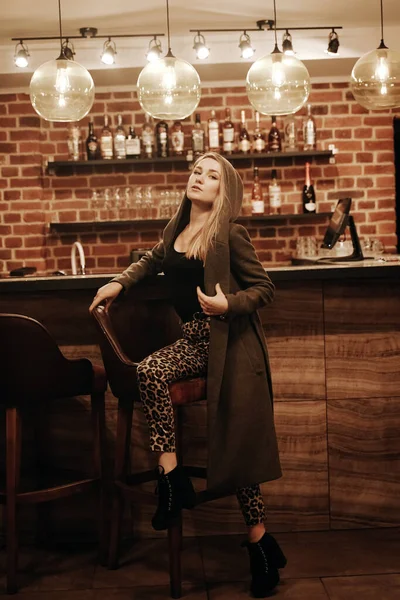 Beauté jeune femme en manteau à capuchon portrait dans un bar de nuit seul — Photo