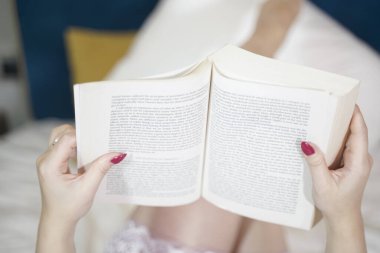 Kitabı olan hoş bir retro kadın yatakta kitap okuyarak ve eğitimle eğleniyor. Gecelikli güzel kız yatak odasında..