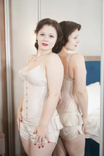 pretty pin up woman near the mirror standing in fashion lingerie