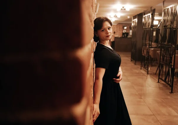 Красива жінка в ретро-сукні проти темної стіни — стокове фото