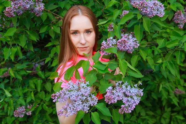 Schöne junge Teen Mädchen steht in den Blumen des Flieders — Stockfoto