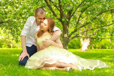 Gelin ve damat elma bahçesinde yürüyorlar, elma ağacının dallarının altında poz veriyorlar..