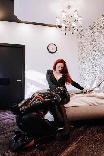 Sexig kvinna med sin latexgummi slav i mask leker hemma i bdsm — Stockfoto