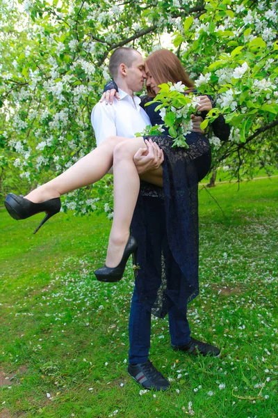 Jeune couple dans le jardin de pommiers verger avec des branches de fleurs marchant ensemble et ont une date Photo De Stock