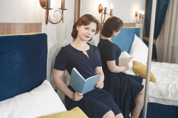 Pin up flicka i blå retro klänning läser en bok — Stockfoto