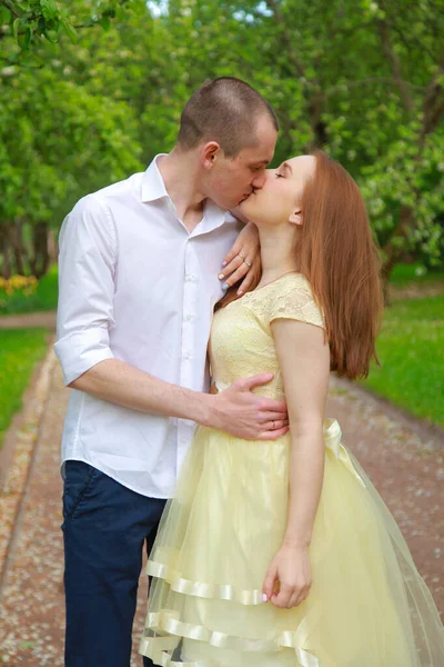 La novia y el novio caminan en el huerto de manzana, colocándose bajo las ramas de un manzano.. — Foto de Stock