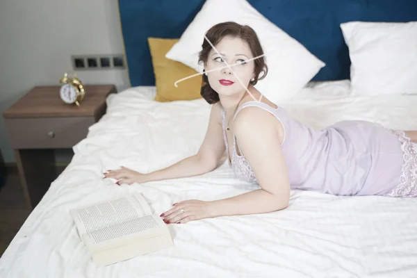 Mignonne femme rétro avec livre profiter par la lecture et l'éducation sur le lit. jolie fille en chemise de nuit dans la chambre . — Photo
