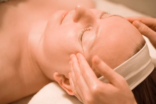 Hermosa mujer de mediana edad más tamaño recibiendo un tratamiento de masaje facial en el salón de belleza. de cerca —  Fotos de Stock