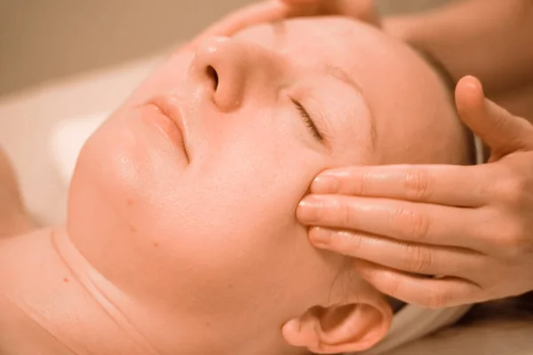 Hermosa mujer de mediana edad más tamaño recibiendo un tratamiento de masaje facial en el salón de belleza. de cerca —  Fotos de Stock