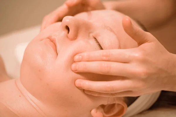 Hermosa mujer de mediana edad más tamaño recibiendo un tratamiento de masaje facial en el salón de belleza. de cerca — Foto de Stock