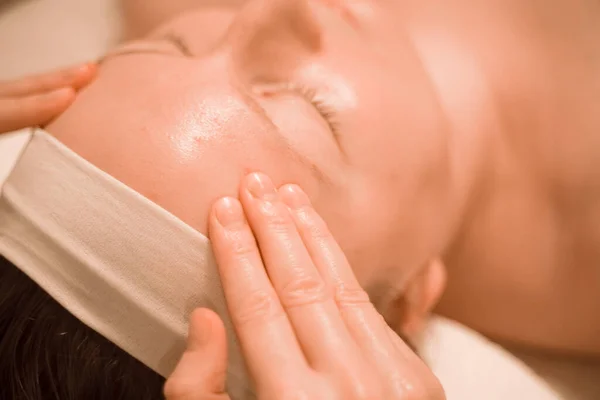 Hermosa mujer de mediana edad más tamaño recibiendo un tratamiento de masaje facial en el salón de belleza. de cerca —  Fotos de Stock