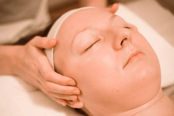 Hermosa mujer de mediana edad más tamaño recibiendo un tratamiento de masaje facial en el salón de belleza. de cerca —  Fotos de Stock