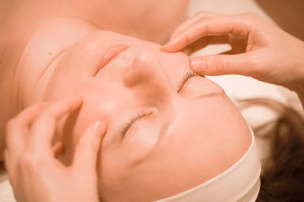 Mulher bonita plus size meia idade recebendo um tratamento de massagem facial no salão de beleza. de perto — Fotografia de Stock