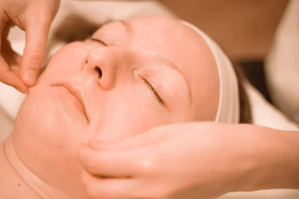 Hermosa mujer de mediana edad más tamaño recibiendo un tratamiento de masaje facial en el salón de belleza. de cerca — Foto de Stock