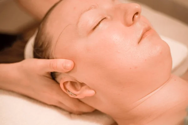 Hermosa mujer de mediana edad más tamaño recibiendo un tratamiento de masaje facial en el salón de belleza. de cerca —  Fotos de Stock