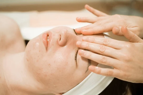 Hermosa joven recibiendo un tratamiento de masaje facial en el salón de belleza — Foto de Stock