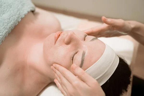 Beautiful young woman getting a face massage treatment at beauty salon