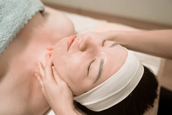 Bella giovane donna ottenere un trattamento di massaggio viso al salone di bellezza — Foto Stock