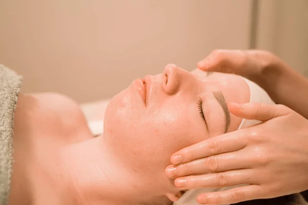 Hermosa joven recibiendo un tratamiento de masaje facial en el salón de belleza —  Fotos de Stock