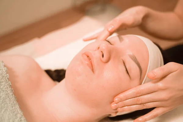 Hermosa joven recibiendo un tratamiento de masaje facial en el salón de belleza —  Fotos de Stock