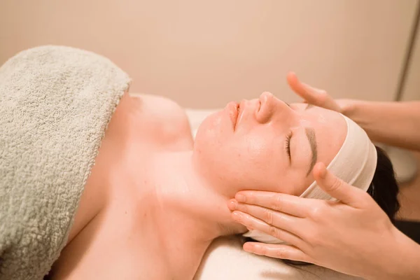 Bella giovane donna ottenere un trattamento di massaggio viso al salone di bellezza — Foto Stock