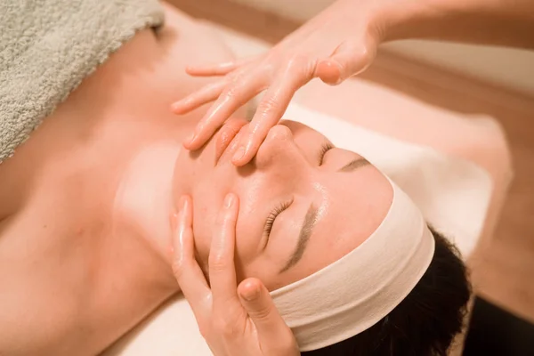 Bella giovane donna ottenere un trattamento di massaggio viso al salone di bellezza — Foto Stock