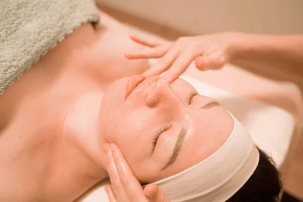 Hermosa joven recibiendo un tratamiento de masaje facial en el salón de belleza —  Fotos de Stock